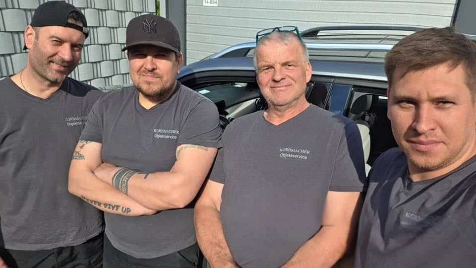 Das Team von Service Korbmacher: vier feste Mitarbeiter in Firmenkleidung vor dem Einsatzfahrzeug in Berlin